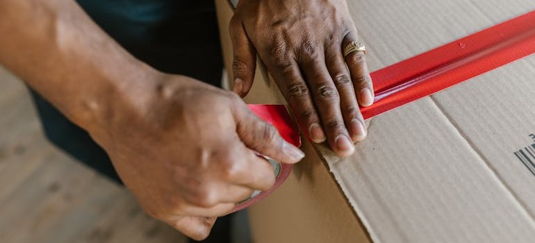 A person from the BR Moving crew putting red tape on a cardboard box