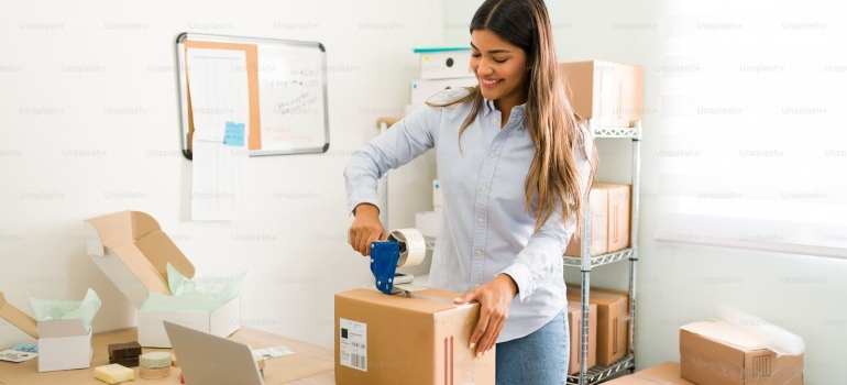 A woman in an office putting a tape on a package