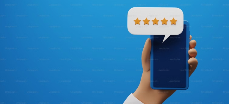 A hand holding a phone with a chat bubble and five stars following the guide to hiring local movers in Philadelphia