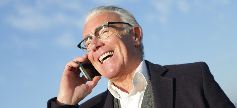A happy senior is having a phone call about the ways to make relocating as a senior less stressful.