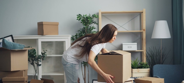 A woman is carrying a cardboard box and thinking about the ways to handle a last-minute move without losing your mind.